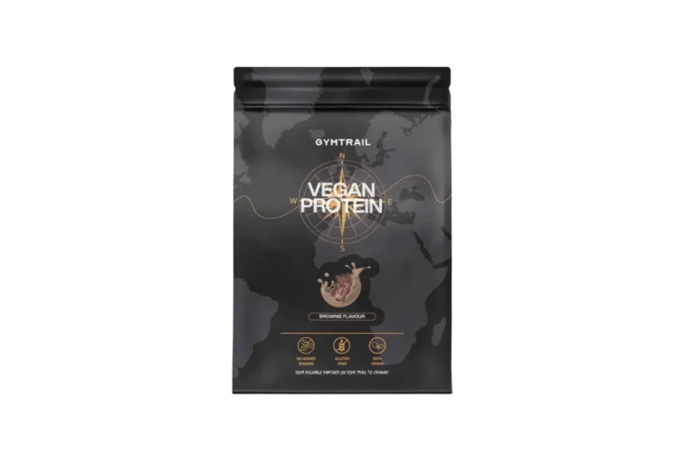 Ein schwarzer, wiederverschließbarer Beutel mit der Aufschrift VEGAN PROTEIN von GYMTRAIL, mit einer Kompassgrafik und "Brownie Flavor". Symbole zeigen an, dass es vegan, sojafrei und ohne Zuckerzusatz ist. Im Hintergrund ist eine Weltkarte abgebildet.